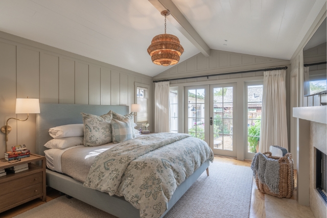 Spacious primary bedroom with fireplace and French doors leading to the patio in Carmel luxury cottage.